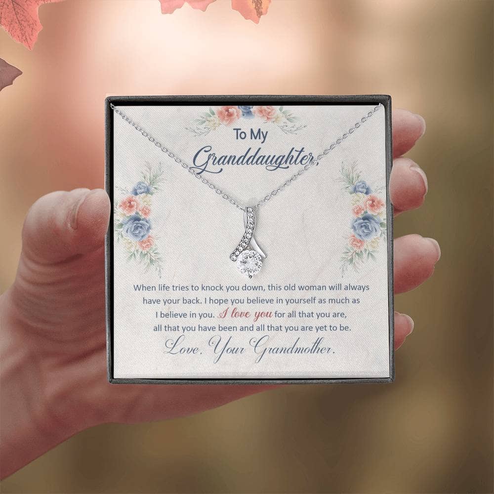 A hand holding a Personalized Keepsake Necklace for Granddaughter, featuring a heart-shaped pendant with a cushion-cut cubic zirconia.