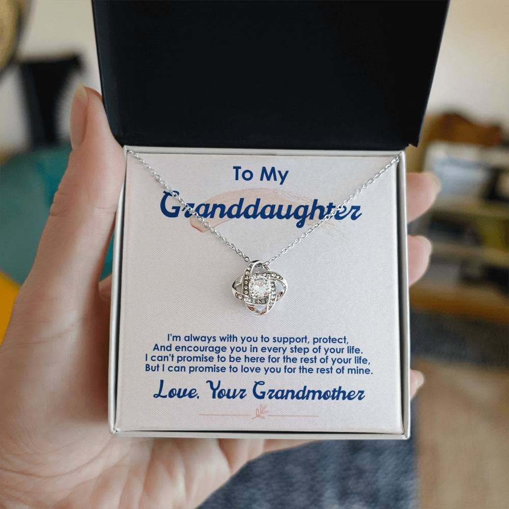 A hand holding a personalized Love Knot Necklace for Granddaughter in a box, symbolizing the enduring bond between grandparents and child.