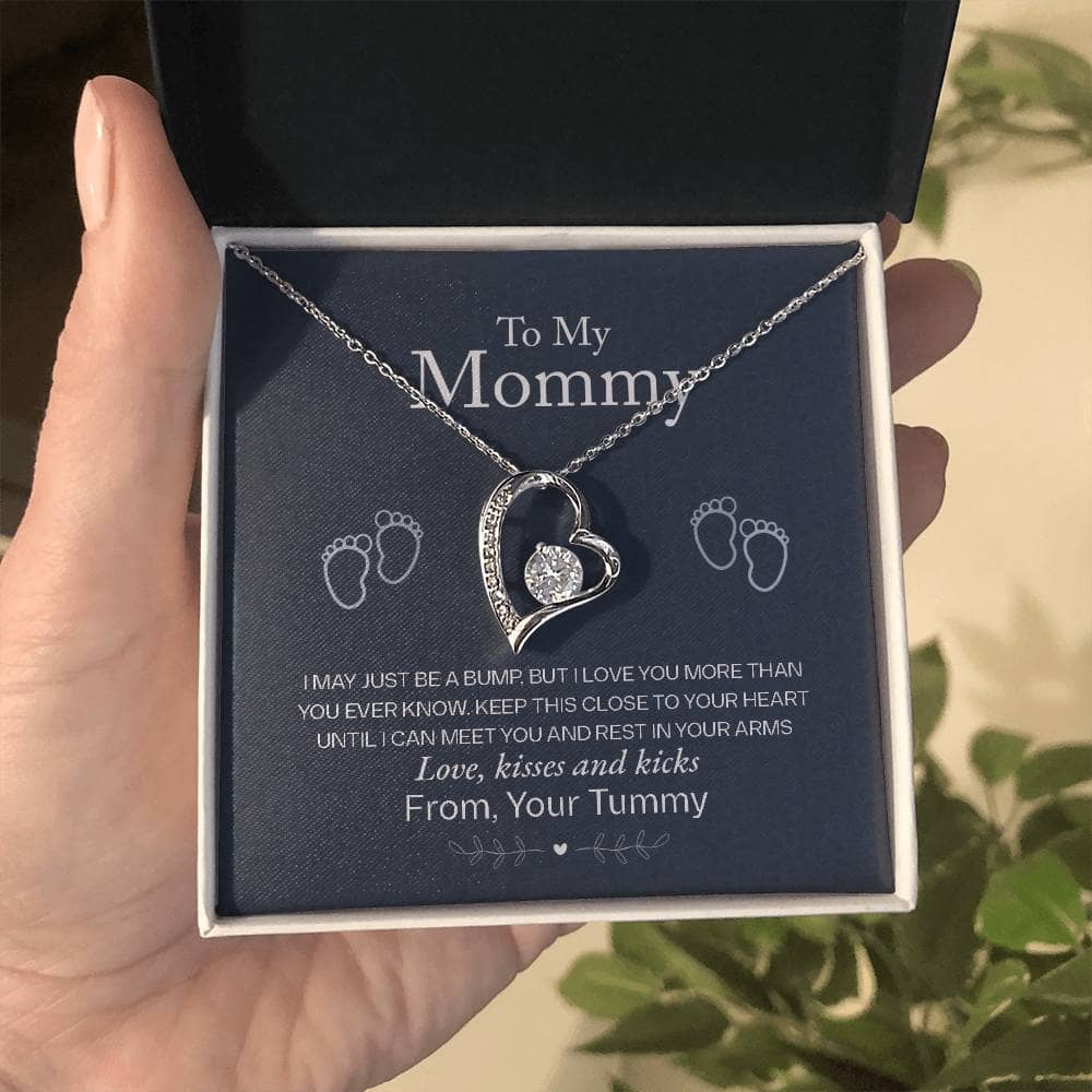 Alt text: "A hand holding a personalized Mother Necklace in a box, symbolizing the enduring love and appreciation from children. The necklace features a heart-shaped pendant with a cushion-cut cubic zirconia, representing the infinite bond between a mother and child."