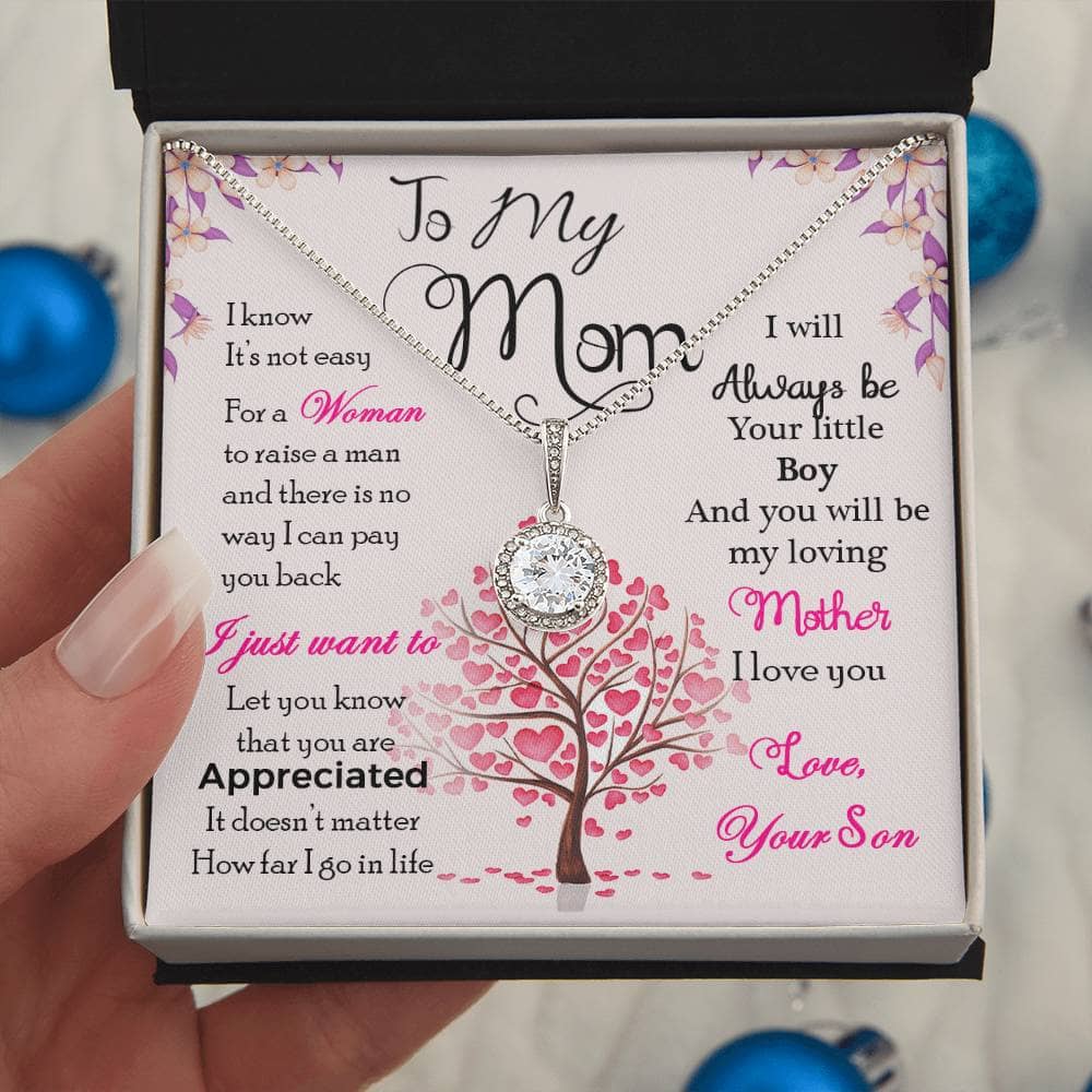 A hand holding a Personalized Mother Necklace in a box, symbolizing the eternal bond between a mother and her children.