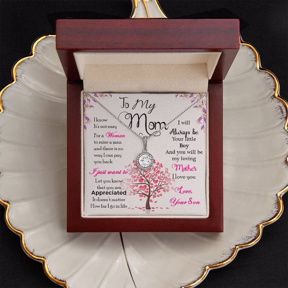 Alt text: "Personalized Mother Necklace - A necklace in a box on a plate, featuring a heart-shaped pendant with a diamond. Celebrate the eternal bond between a mother and her children with this exquisite necklace from Bespoke Necklace."