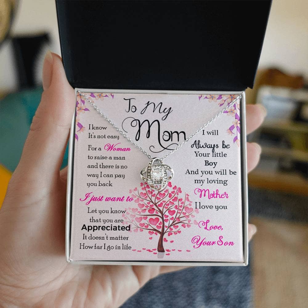Alt text: "A hand holding a Personalized Mother Necklace in a box, symbolizing the strong bond between mothers and their children."
