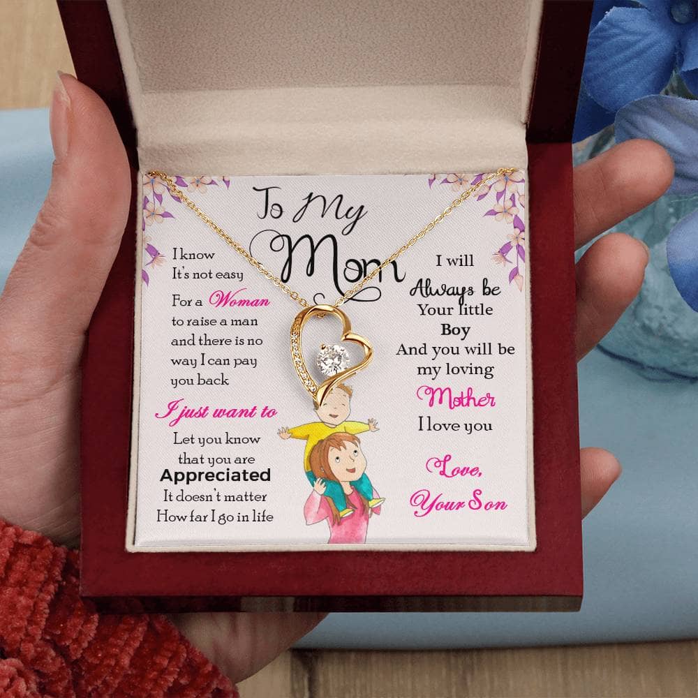 Alt text: "A hand holding a Cherished Mother Personalized Necklace in a box, featuring a heart-shaped pendant with a diamond in the middle. The necklace represents the everlasting bond between mothers and their children."