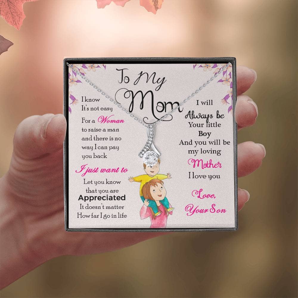 A hand holding a Personalized Mother Necklace - Gift From Son Or Daughter, featuring a heart-shaped pendant with a cushion-cut cubic zirconia.