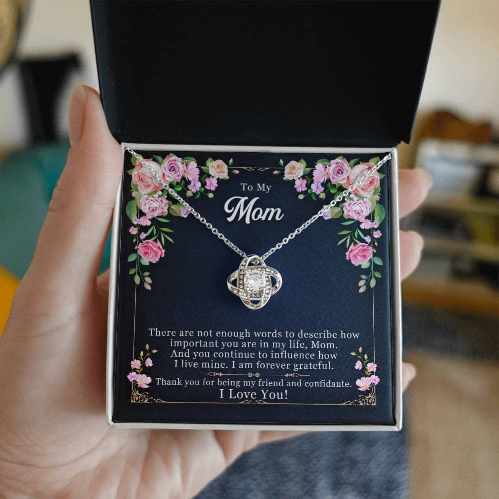A hand holding a Personalized Mother Necklace - Love Knot Gift From Child in a box.