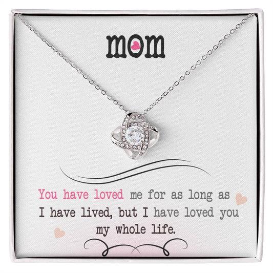 A close-up of a Personalized Mother Necklace - Love Knot Jewelry, featuring a heart-shaped pendant adorned with cubic zirconia crystals.