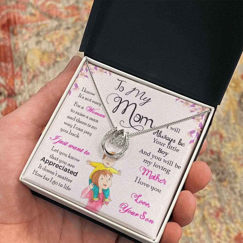 A hand holding a Personalized Mother Necklace in a box, symbolizing the bond between a mother and child.