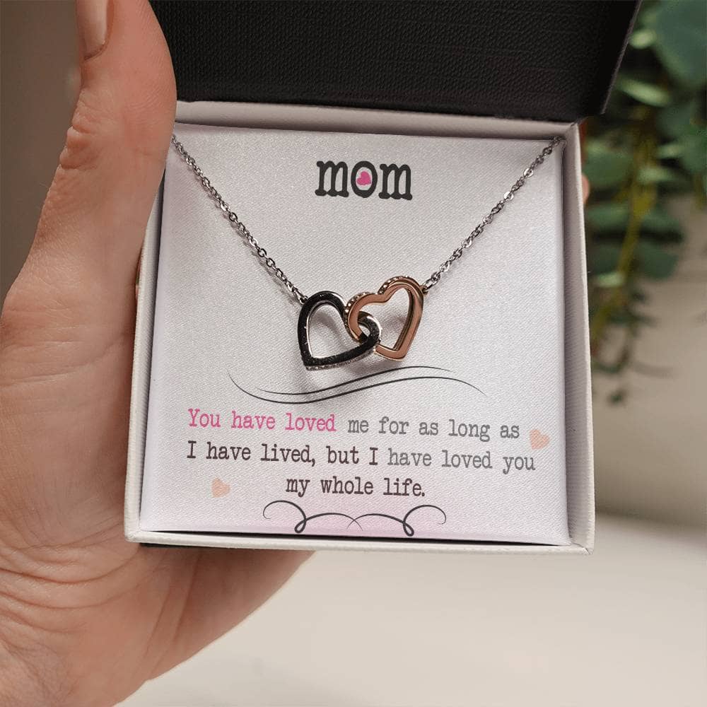 Alt text: "A hand holding a Personalized Mother Necklace with cushion-cut cubic zirconia accents in a box"