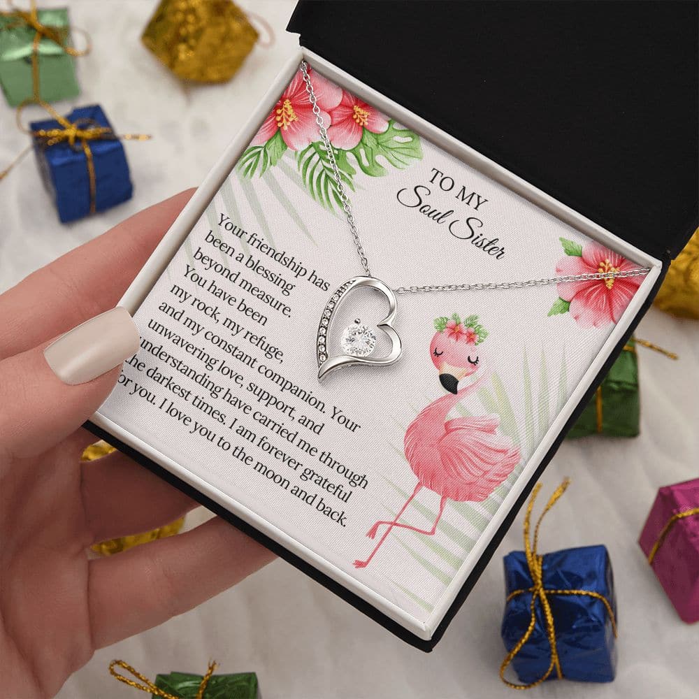 Alt text: "A hand holding a heart-shaped pendant necklace in a box, symbolizing the inseparable bond between soul sisters."