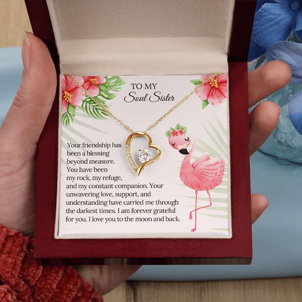 Alt text: "A hand holding a personalized Soul Sister Necklace, featuring a heart-shaped pendant with cubic zirconia crystals. Available in white gold or yellow gold. Adjustable chain length of 18" - 22". Packaged in a soft touch box. Celebrate your unbreakable bond with your sister."