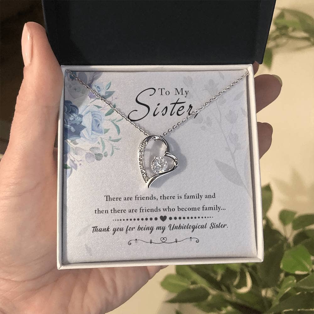 A hand holding a Personalized Soul Sister Necklace with an elegant heart pendant in a box.