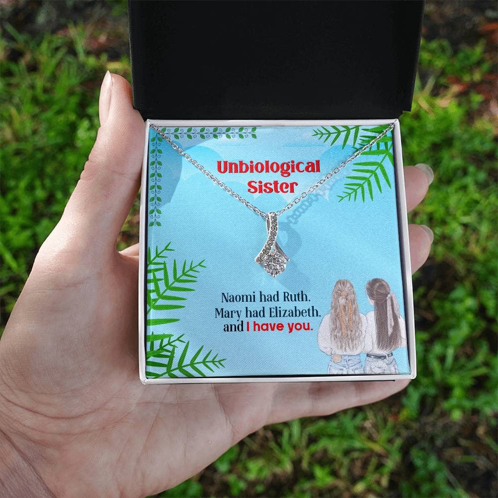 Alt text: "Hand holding Personalized Unbiological Sisters Necklace in a box"