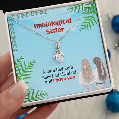 A hand holding a Personalized Unbiological Sisters Necklace, featuring a pendant with intertwined hearts or a love knot design.