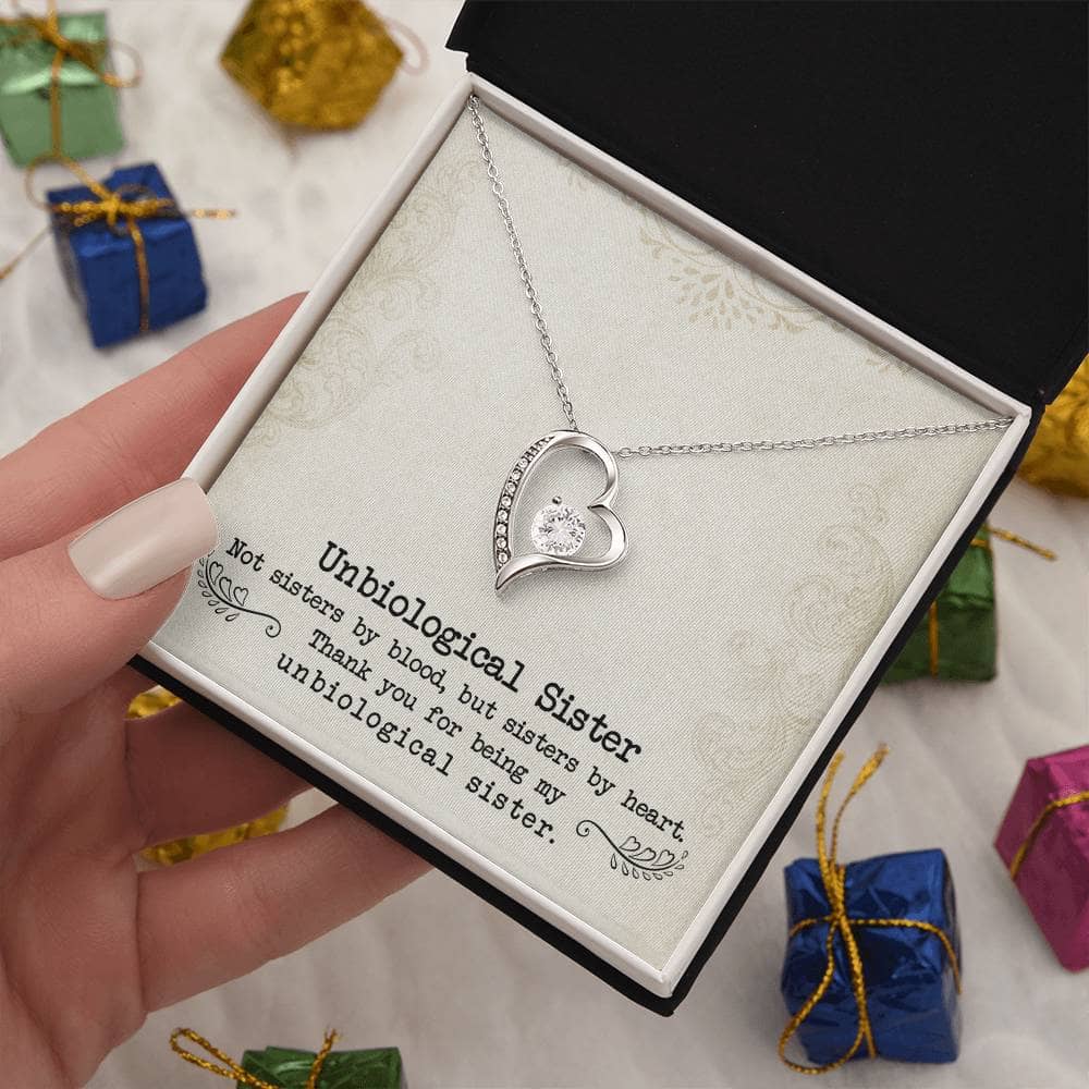 A hand holding a Personalized 'Unbiological Sisters' Forever Love Necklace in a box, symbolizing the everlasting bond of sisterhood.