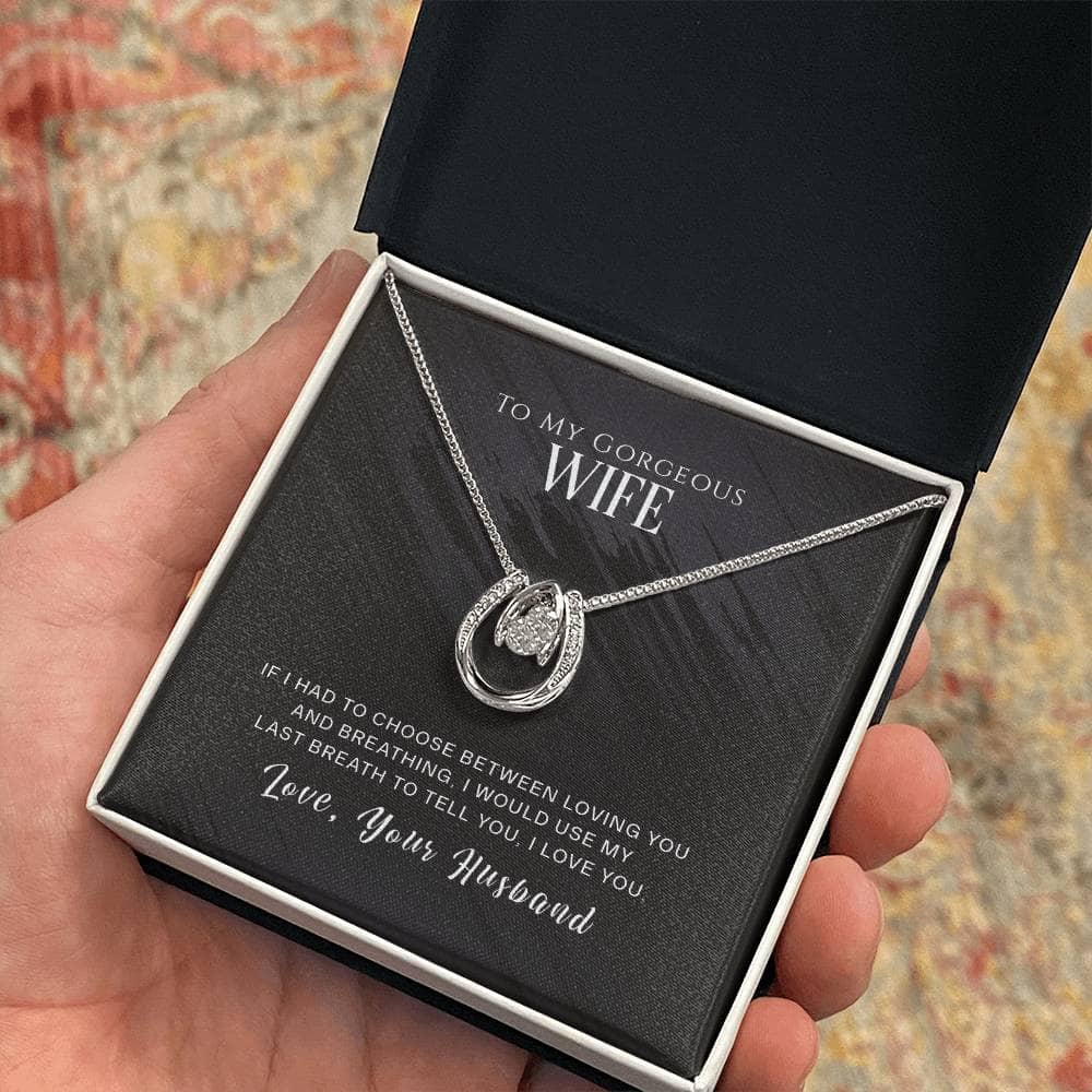 A hand holding a Personalized Wife Necklace in a box, featuring a heart-shaped pendant made of cushion-cut cubic zirconia.