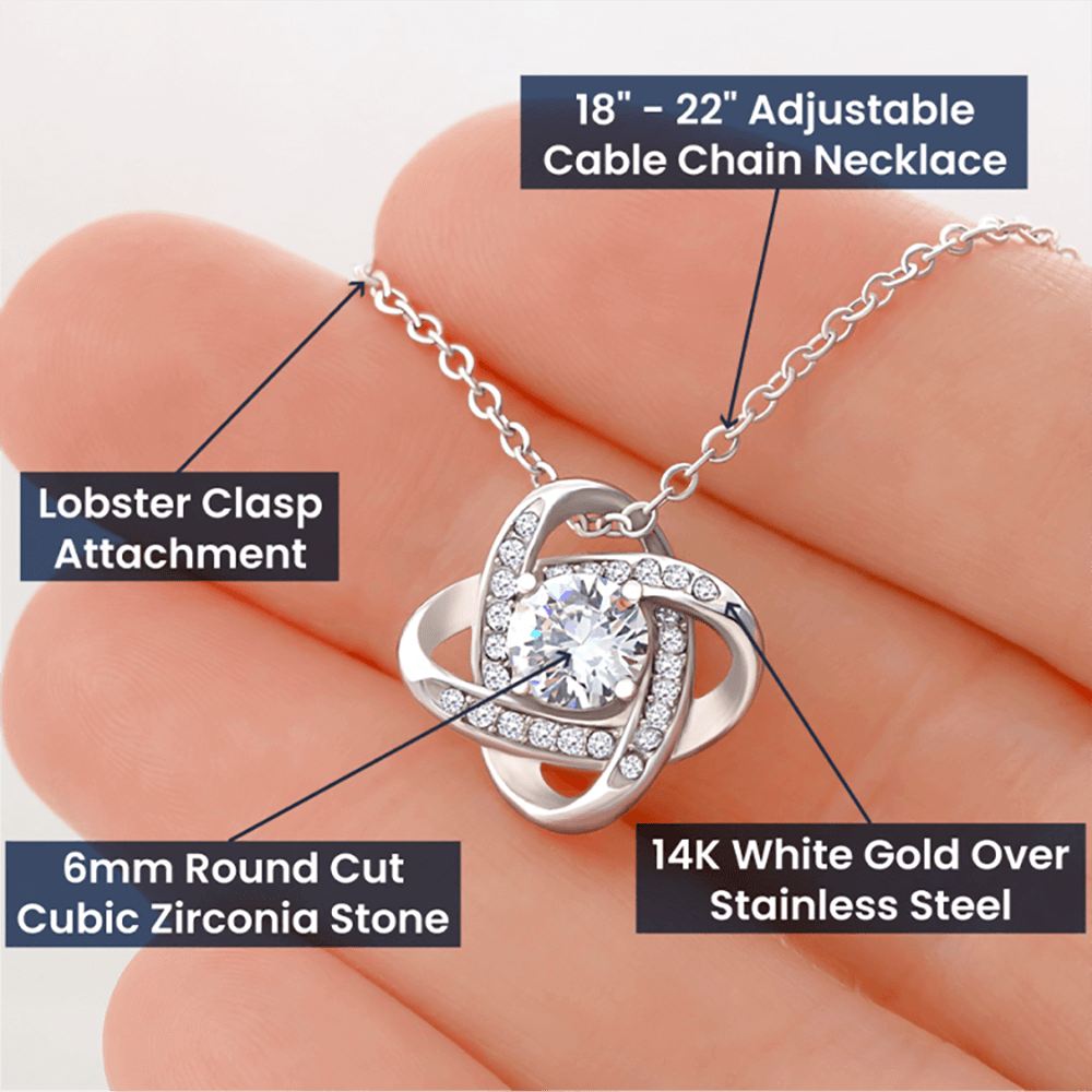 Alt text: "A hand holding a Love Knot Necklace with instructions, a symbol of endless love and devotion. Crafted with cubic zirconia, this necklace showcases elegance and resilience. Adjustable chain included."