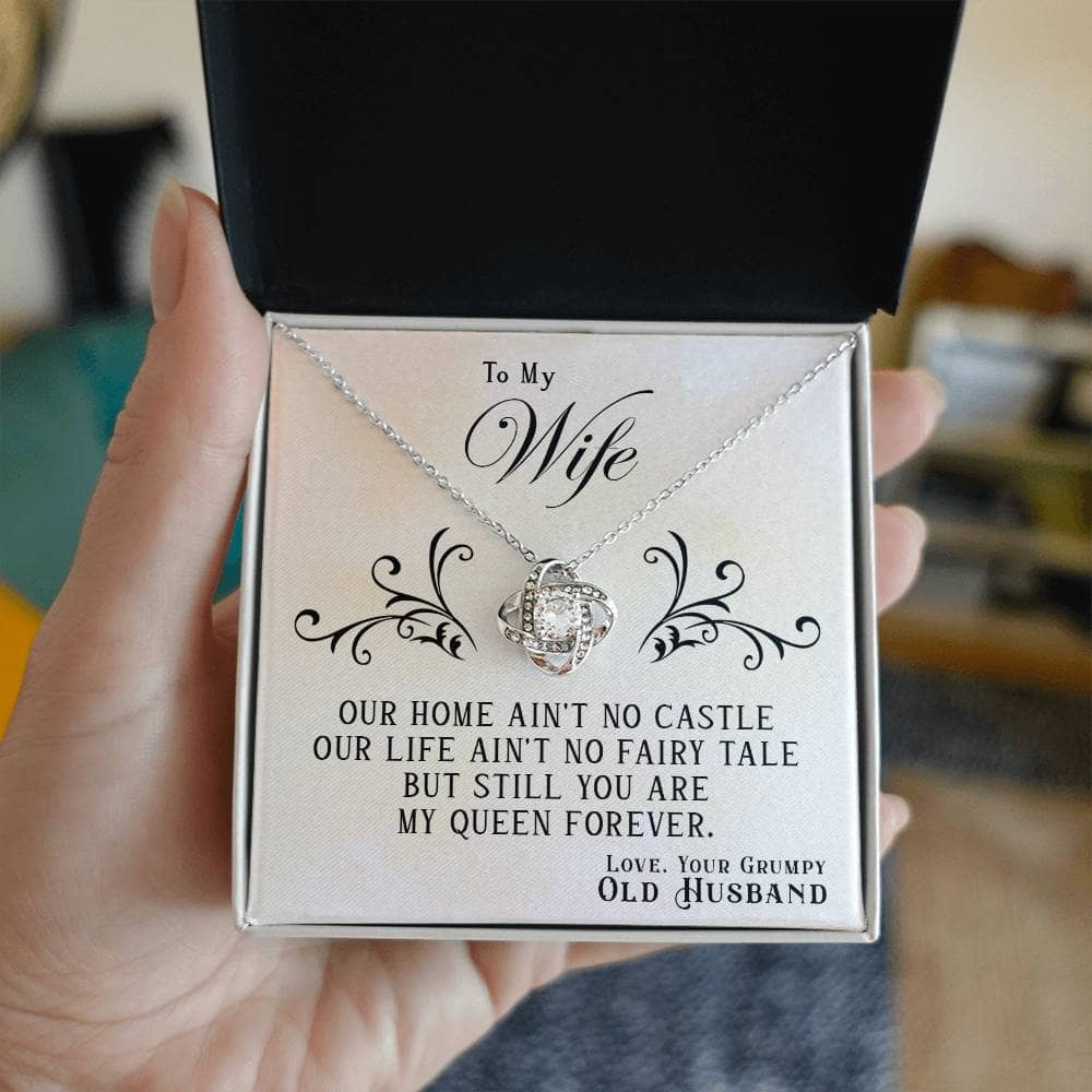 Alt text: "Hand holding a personalized wife necklace in a box, showcasing a graceful heart knot embrace design."