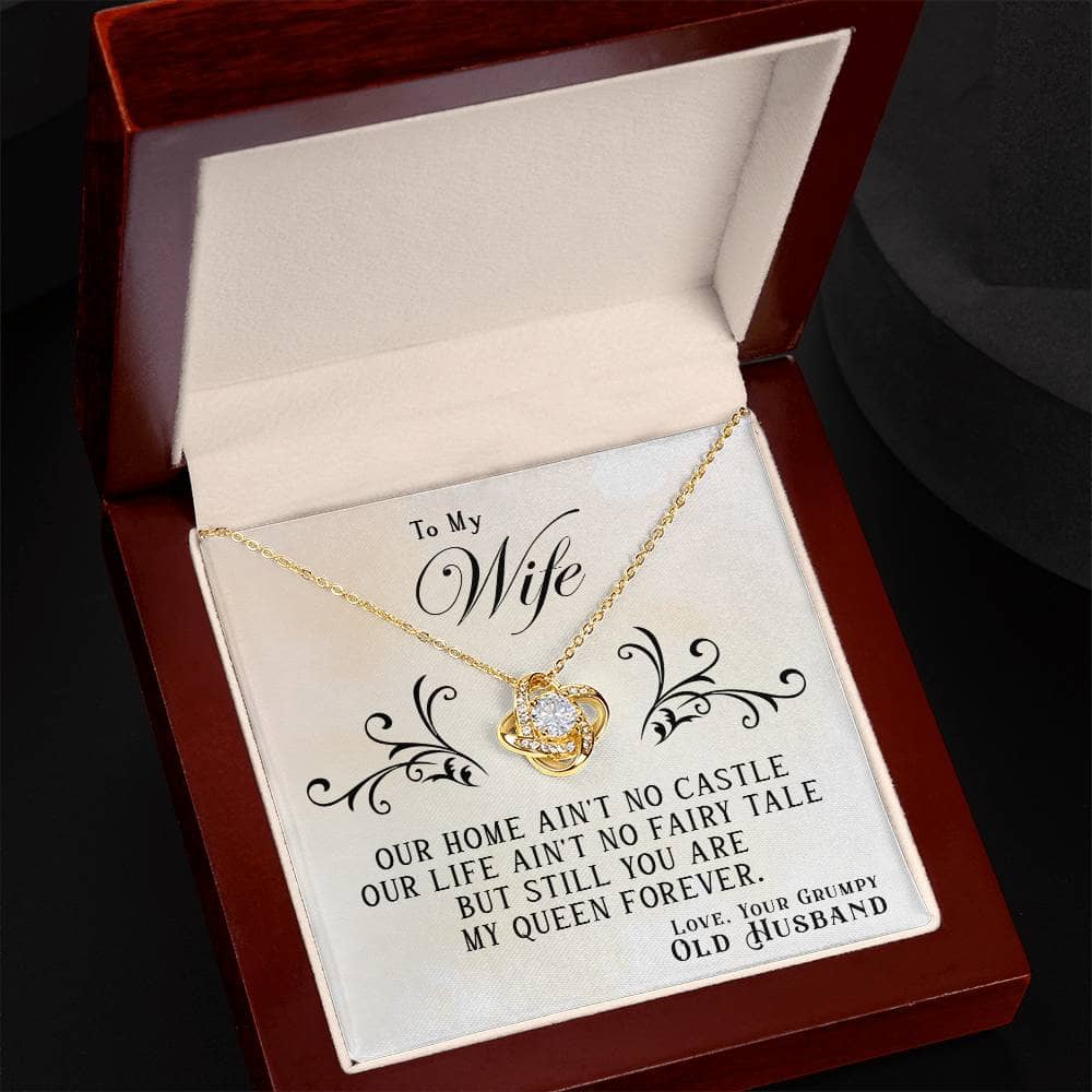 A gold necklace in a box, featuring a heart-shaped pendant and glistening cubic zirconia stone. Personalized Wife Necklace - Graceful Heart Knot Embrace.