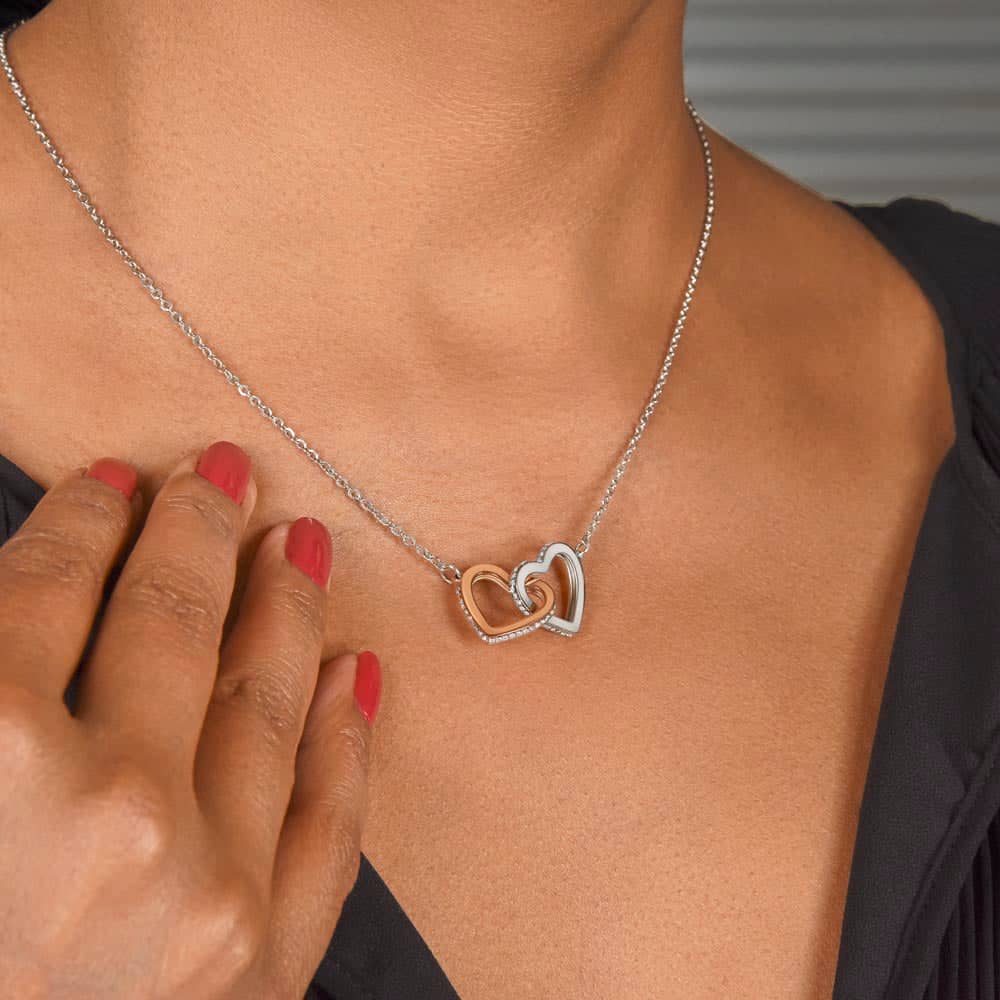 Woman wearing a heart-shaped pendant necklace, touching it gently.