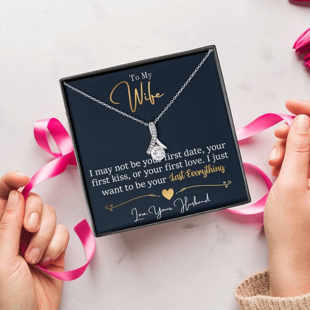 Alt text: "Close-up of Personalized Wife Necklace: Symbol Of Love And Connection, a ribbon-shaped pendant in a box, held by hands"