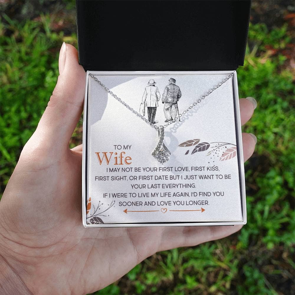 Alt text: "Hand holding a box with a personalized wife necklace, featuring a heart pendant and cubic zirconia."
