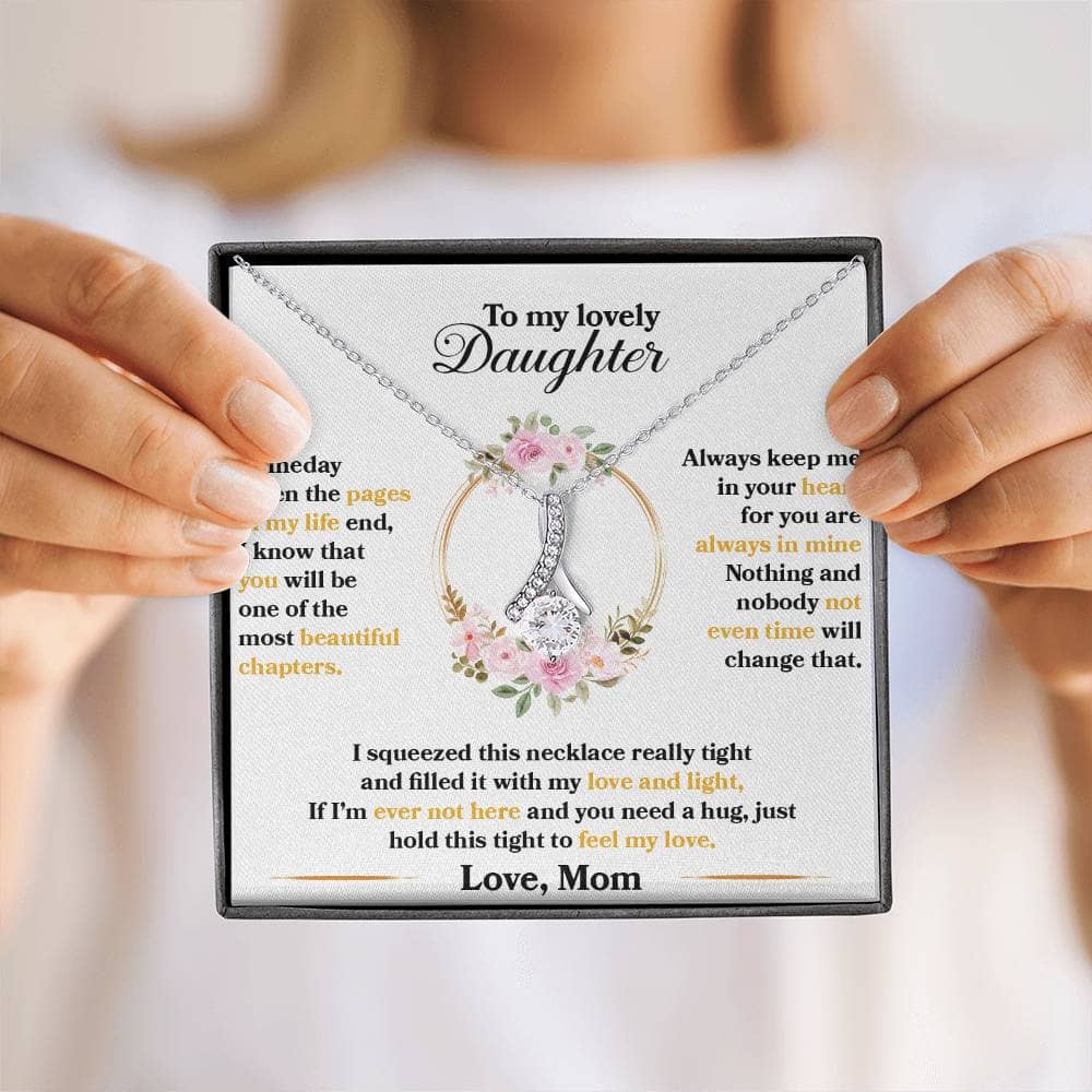 Alt text: "A person holding a personalized daughter necklace, symbolizing an unyielding bond. Intricately adorned with cubic zirconia, this necklace radiates sophistication and resilience. Adjustable chains cater to unique tastes. Arrives in a luxurious mahogany-style box with LED lighting."