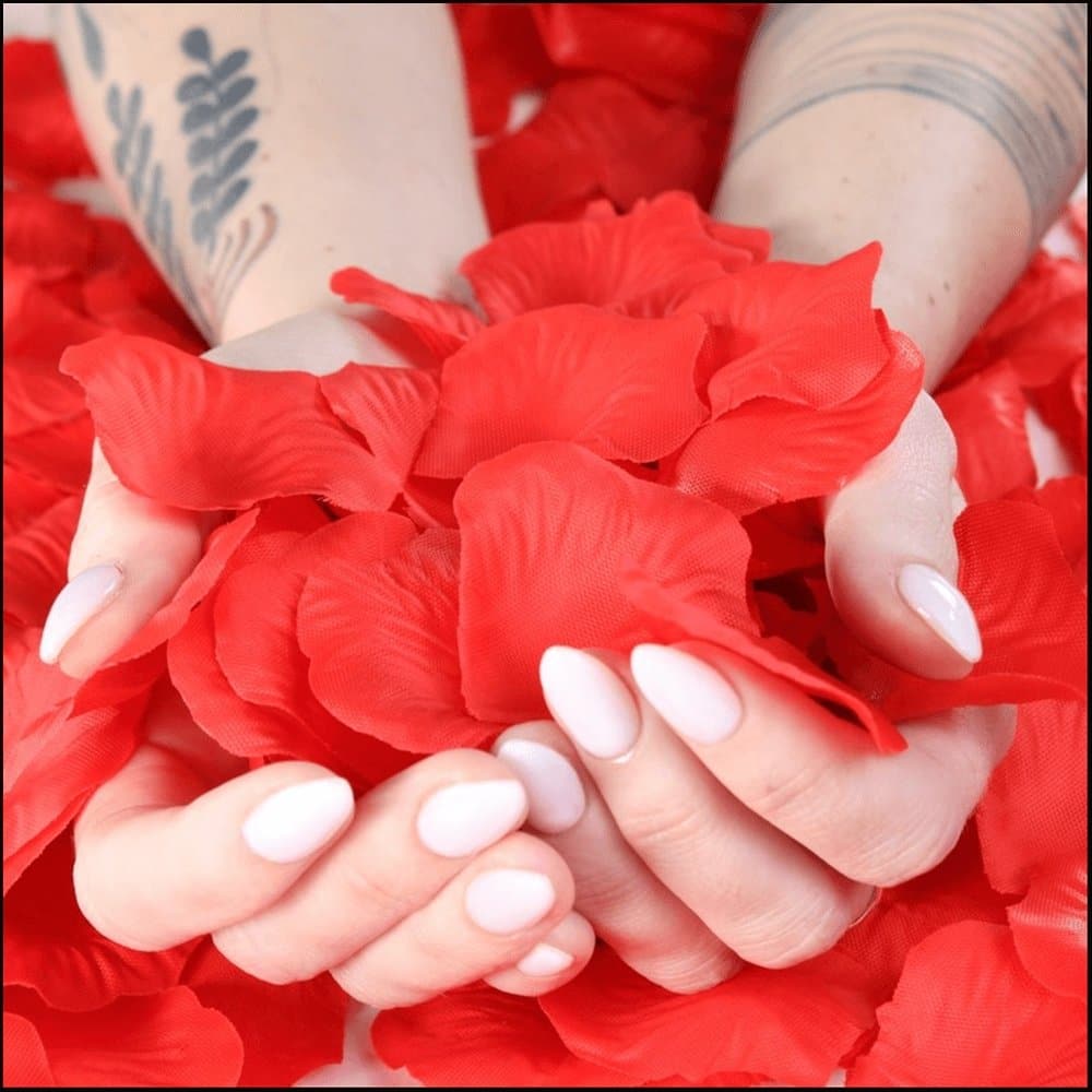 A person's hands holding a pile of lifelike red rose petals, perfect for elevating the moment. Rose Petals by Bespoke Necklace.