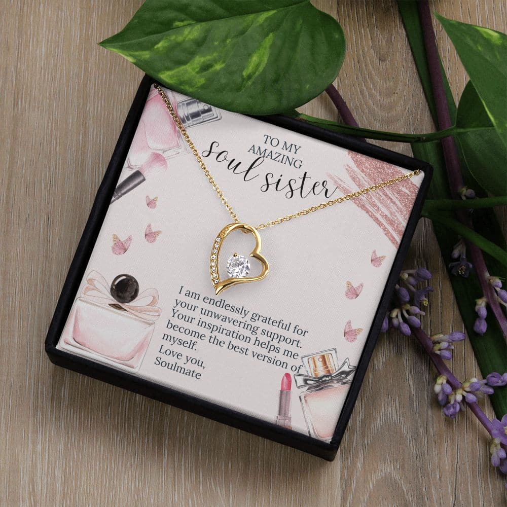 Alt text: "Soul Sister Unity Necklace Set: A necklace in a box with leaves, featuring a gold heart pendant with a diamond and purple flowers on a stem."