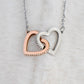 A close-up of a Special Soulmate - Interlocking Hearts Custom Necklace, featuring two gold and silver hearts intertwined.
