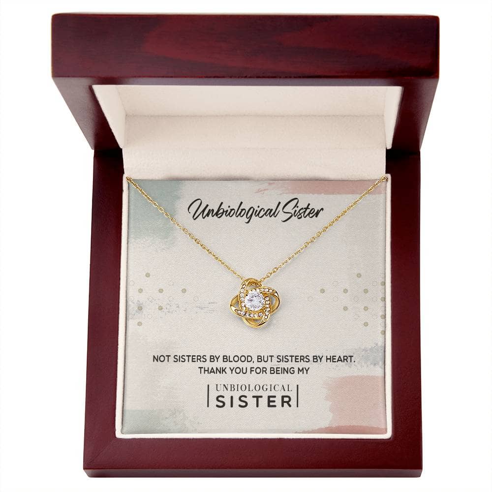 Alt text: "Unbiological Sister" Custom Love Knot Pendant in a box, adorned with cubic zirconia, 14k white gold or 18k gold finish.