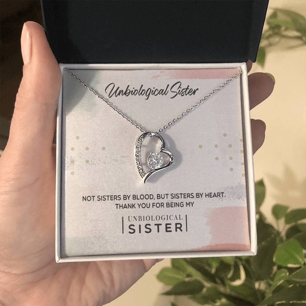 Alt text: "A hand holding a heart-shaped pendant necklace with a diamond, symbolizing the unbreakable bond of unbiological sisters."