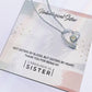 A close-up of the heart-shaped Unbiological Sister Tribute necklace, elegantly bejeweled with cubic zirconia on a card.